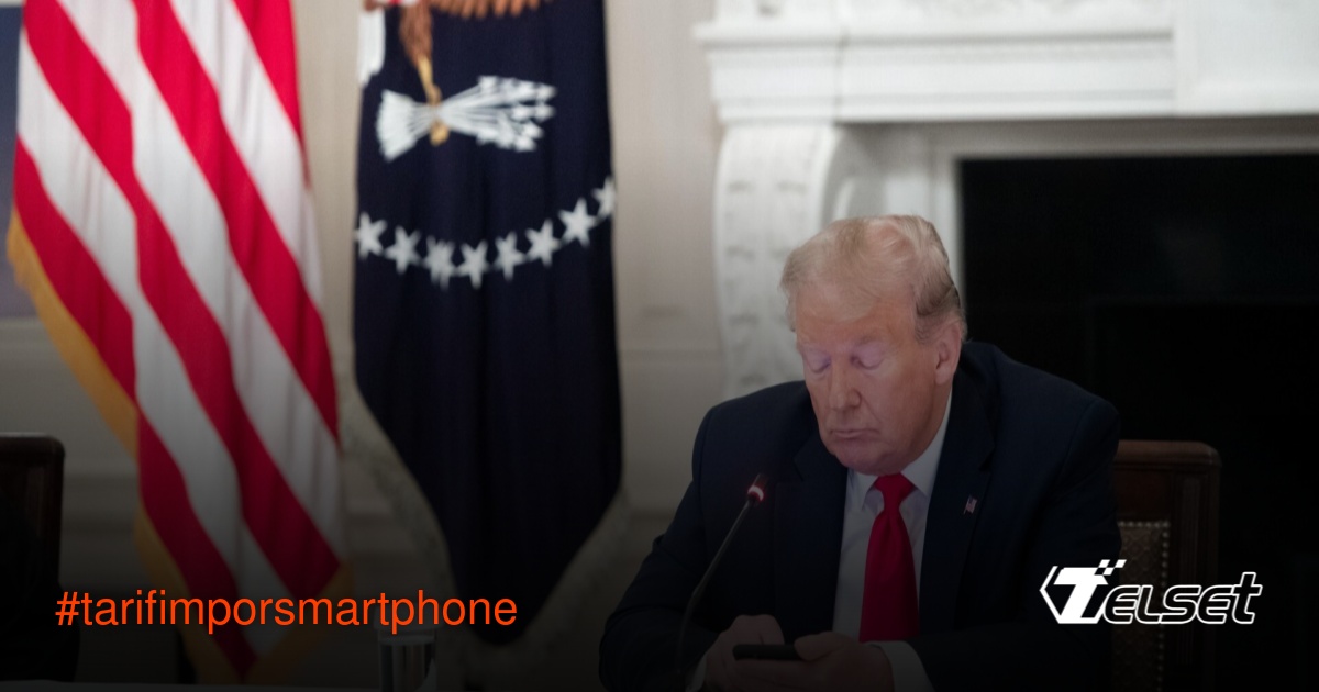 Donald Trump memegang smartphone sambil duduk di meja kerja