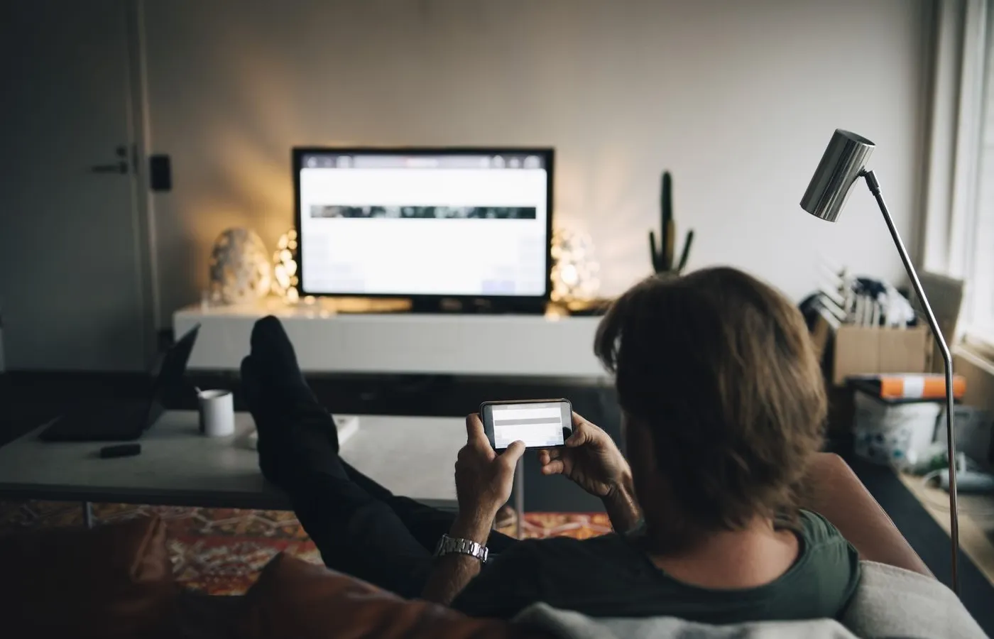 Orang menggunakan smartphone sambil menonton TV dengan Chromecast