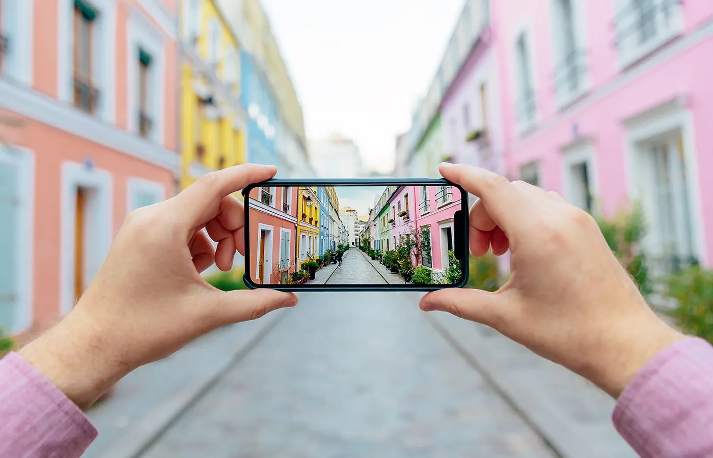 Ilustrasi seseorang memotret jalanan Rue Cremieux di Paris menggunakan smartphone, merepresentasikan pengujian aplikasi mobile.