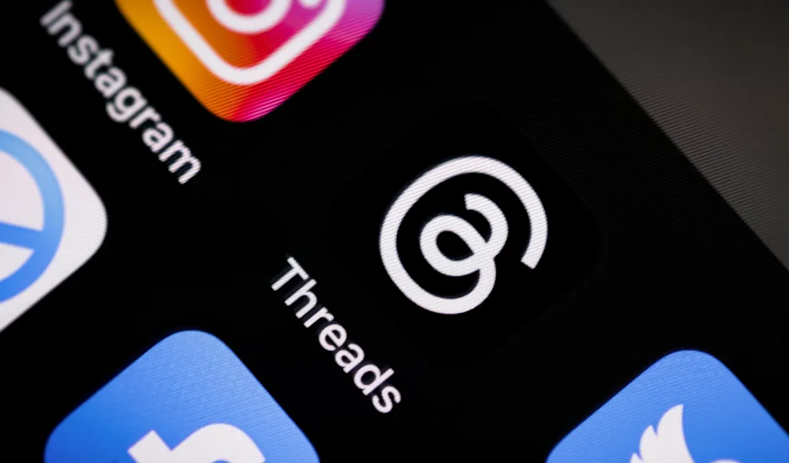 Ilustrasi persaingan aplikasi Threads dan X di layar ponsel pintar