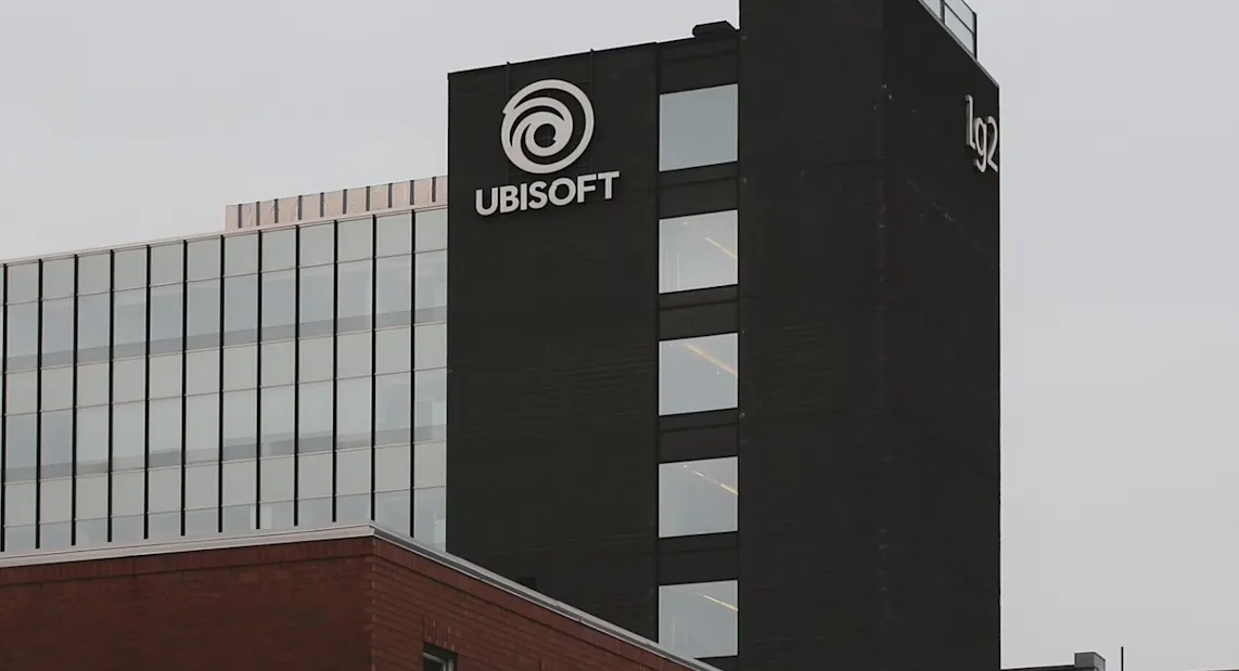 Logo Ubisoft di gedung kantor pusat dengan latar langit biru cerah.
