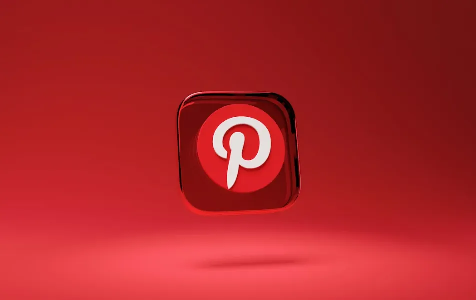 Ilustrasi logo Pinterest di smartphone dengan latar belakang buram, menggambarkan berita Pinterest pangkas karyawan demi fokus AI.