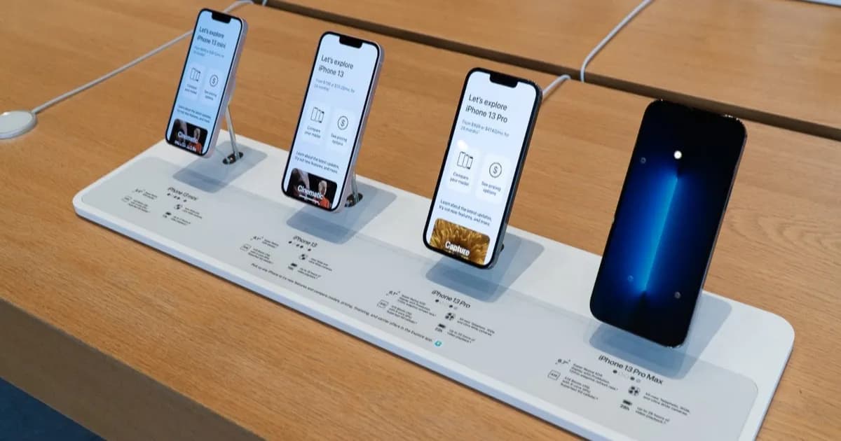 iPhones lined up on a table at an Apple Store.