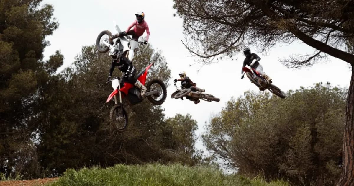 Stark Varg MX melompat di jalur off-road dengan latar belakang hutan
