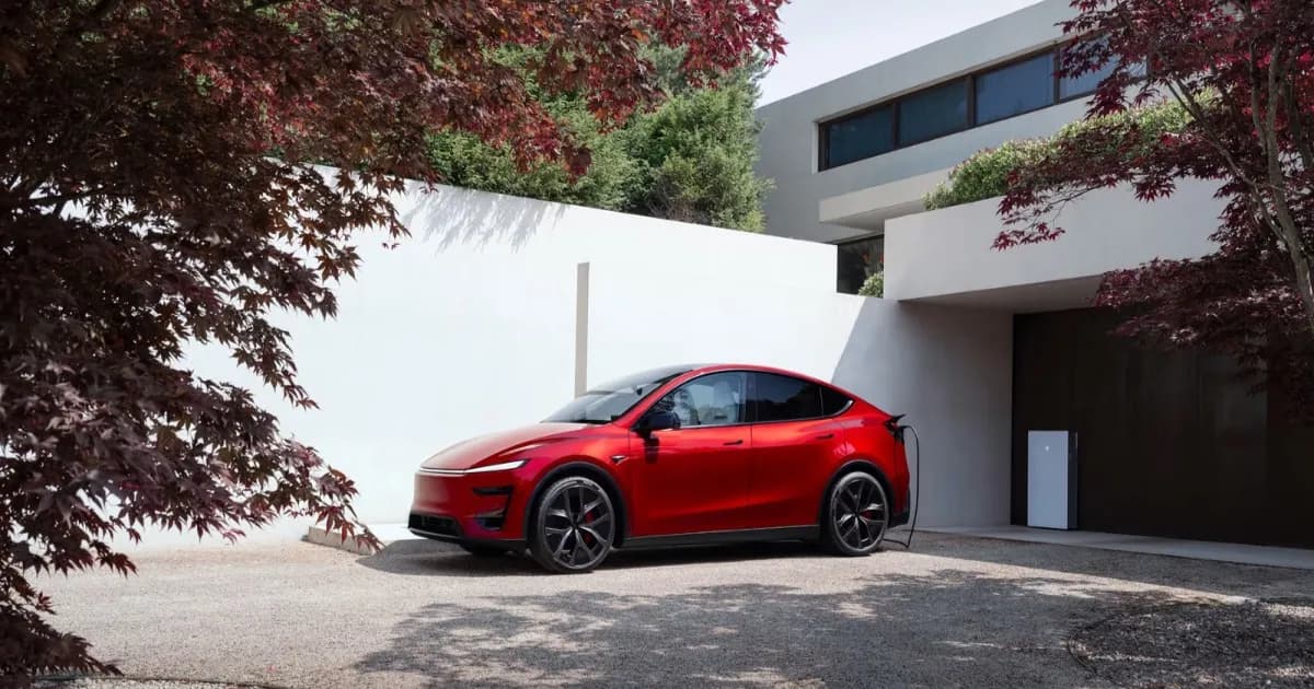 Tesla Model Y sedang diisi daya di rumah dengan latar garasi yang rapi.