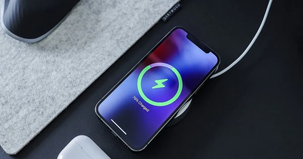 Ilustrasi wireless charger dan smartphone dengan logo Apple, Google, dan Xiaomi