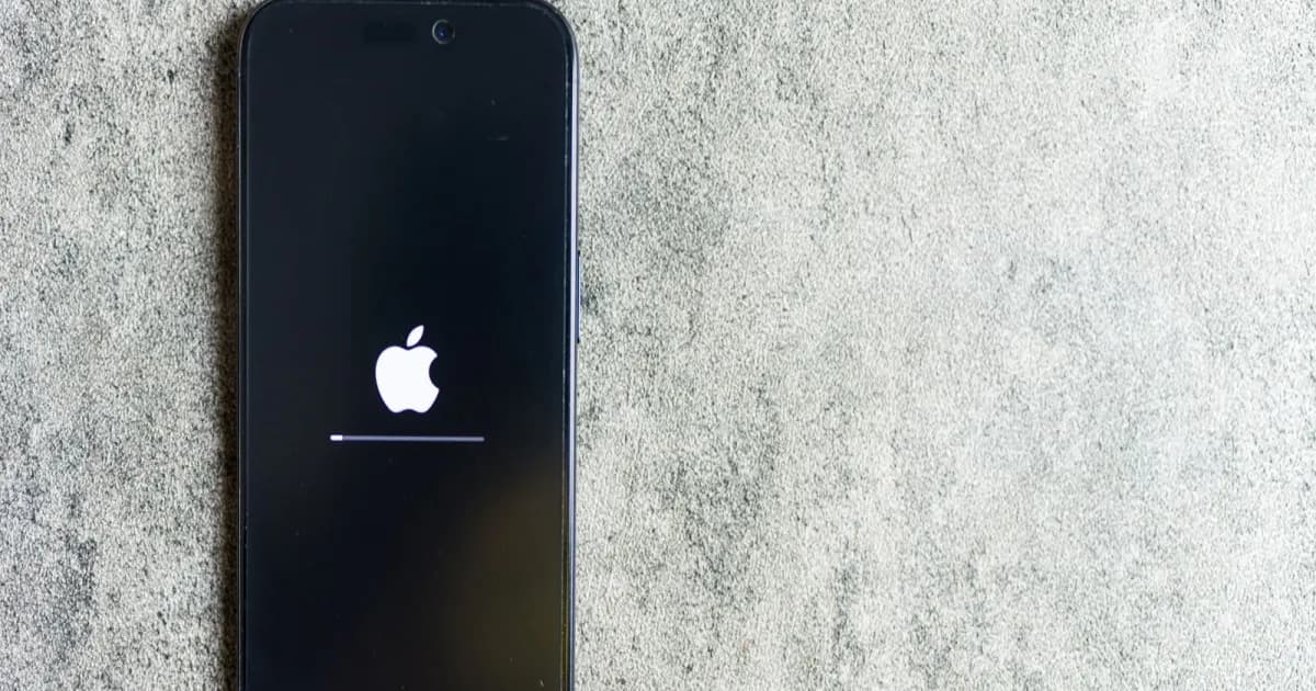 Ilustrasi iPhone dengan logo Apple dan latar belakang abu-abu, menyoroti fitur Hide My Email.