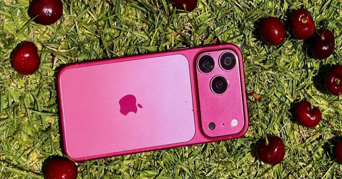 iPhone 18 Pro dalam warna Dark Cherry dengan latar rumput dan buah ceri di sekitarnya.