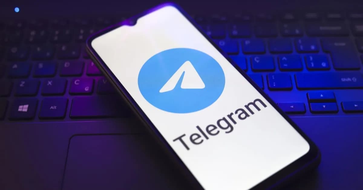 Logo Telegram muncul di layar smartphone yang bertumpu di atas keyboard laptop
