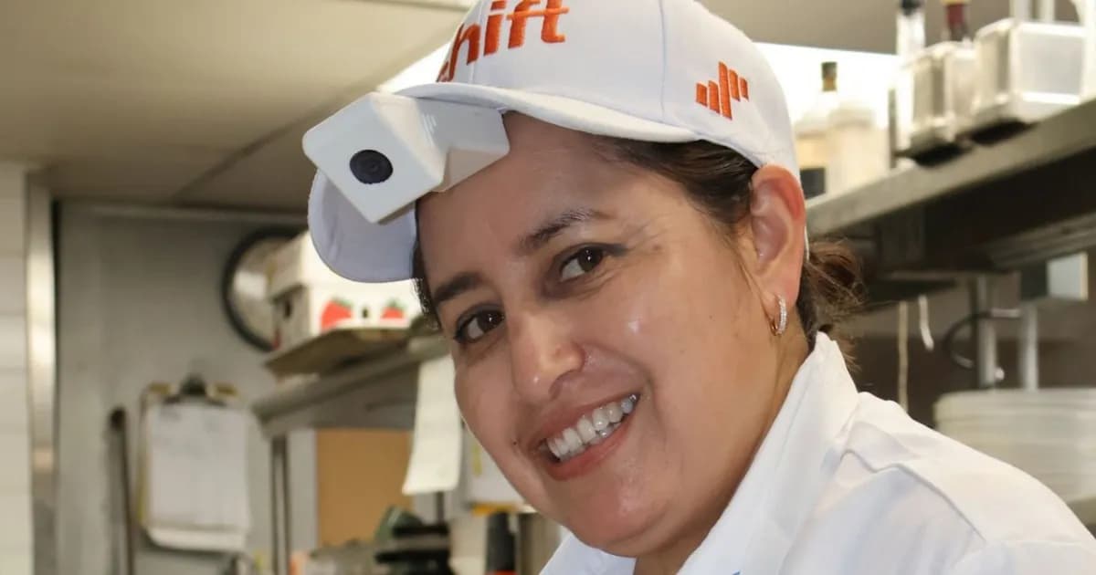 Koki Shift dengan kamera di topi sedang memasak salmon di dapur apartemen