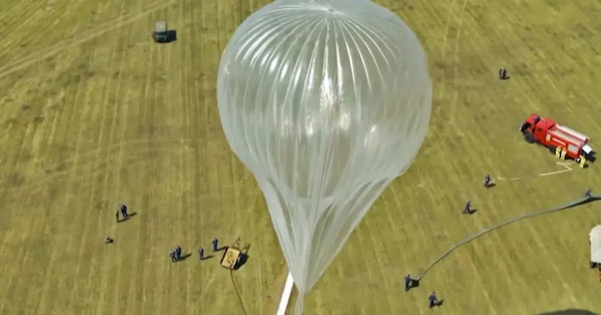 Balon stratosfer ketinggian tinggi sedang disiapkan untuk peluncuran di lapangan terbuka dengan kru darat di sekitarnya