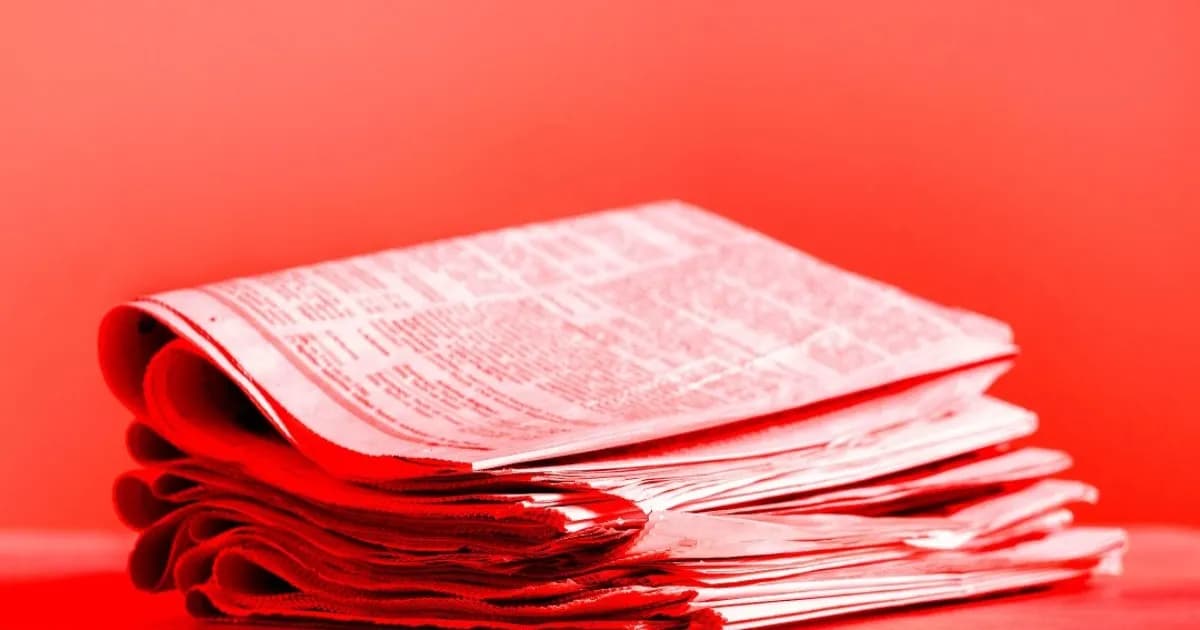 Tumpukan koran dengan foto berwarna yang menggambarkan industri media cetak