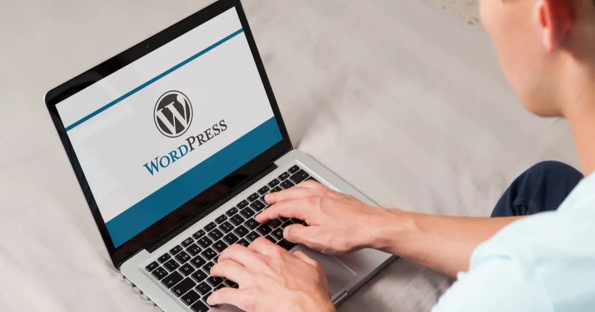 Ilustrasi logo WordPress di layar komputer dengan pengguna mengetik di keyboard