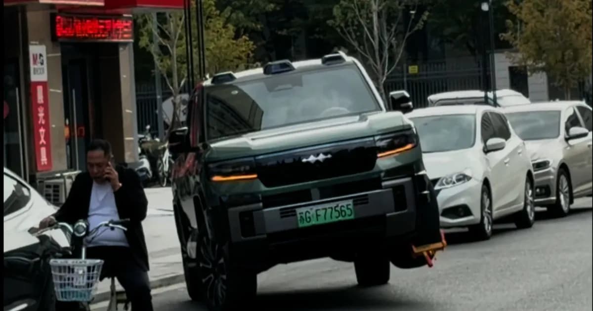 BYD Fang Cheng Bao Bao 8 melaju dengan tiga roda dan wheel clamp kuning-merah terpasang di roda depan kiri yang terangkat
