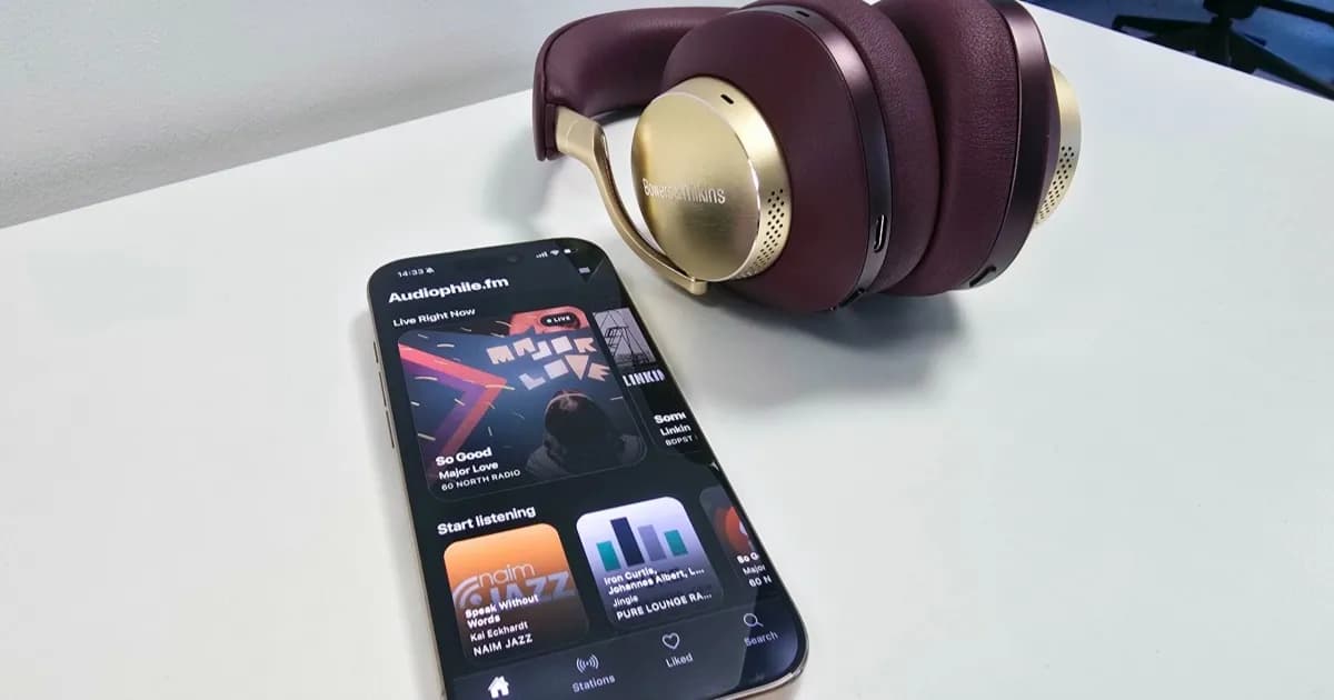 Aplikasi Audiophile.fm pada layar iPhone di samping headphone Bowers & Wilkins