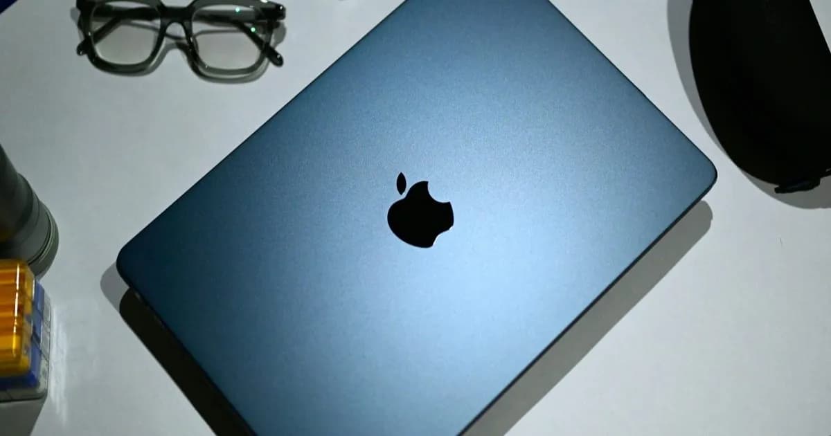 MacBook Air dengan layar menampilkan pemandangan pepohonan di latar belakang