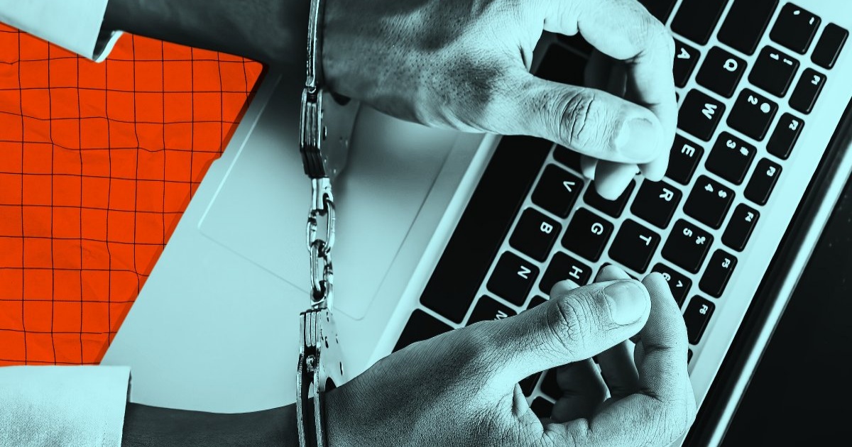 Tangan diborgol mengetik di keyboard laptop dengan latar belakang pola kotak-kotak oranye.