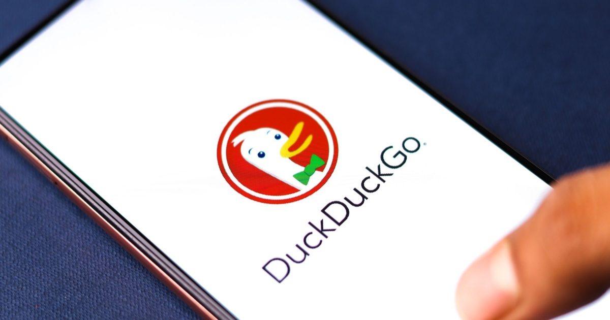 Logo DuckDuckGo di layar ponsel dengan latar belakang pencarian