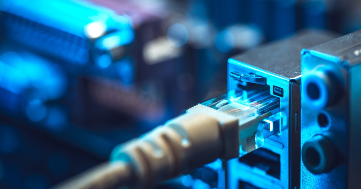 Foto kabel Ethernet yang dicolokkan ke stopkontak logam.