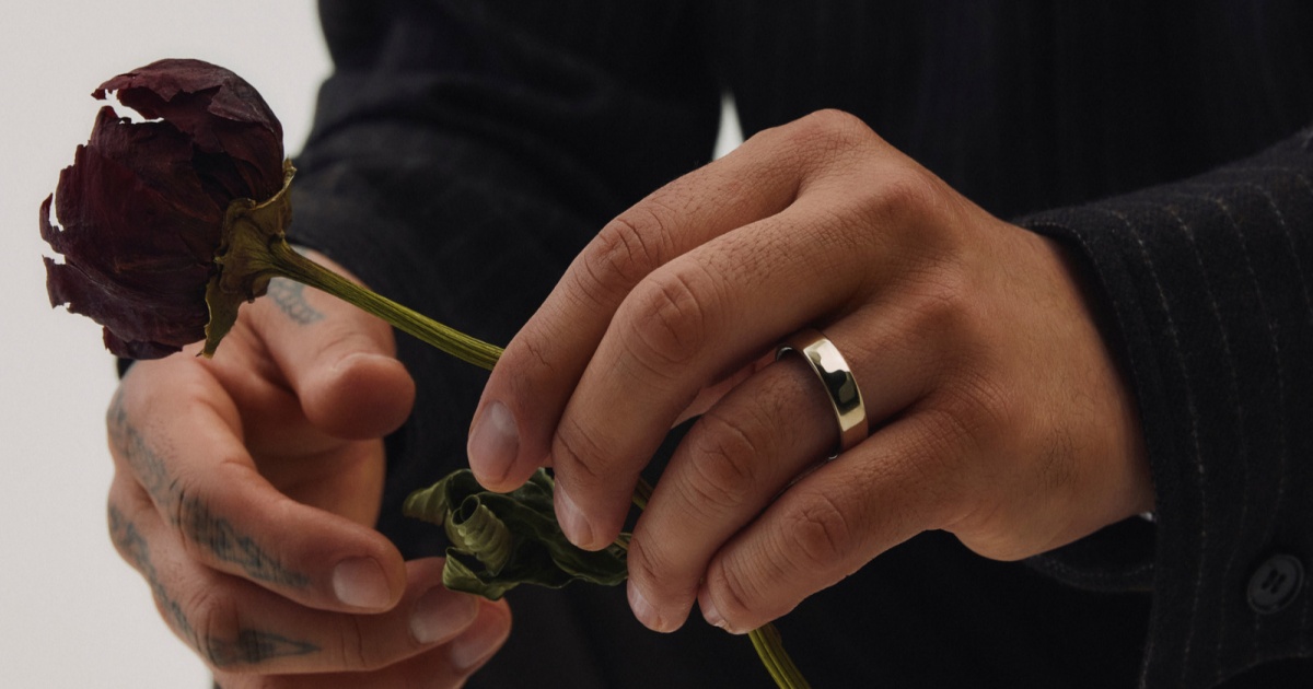 Oura Ring 5 dipakai di tangan model sambil memegang bunga kering