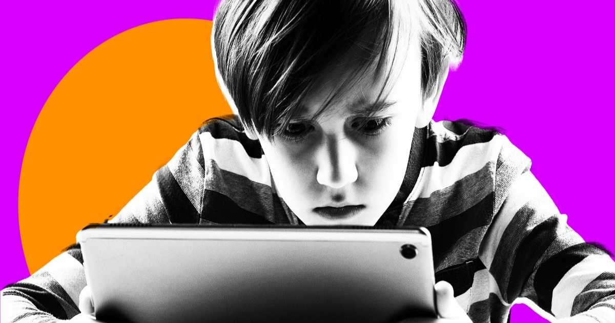 Seorang anak laki-laki fokus memegang tablet dengan latar belakang ungu
