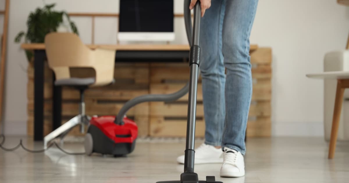 Orang sedang membersihkan lantai dengan vacuum cleaner