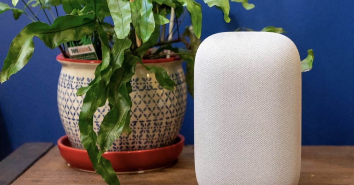 Google Nest Audio speaker di samping tanaman hias dalam pot keramik besar