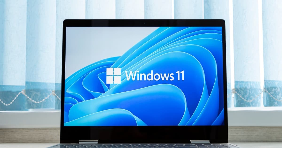 Laptop menampilkan logo Windows 11 dengan latar belakang biru