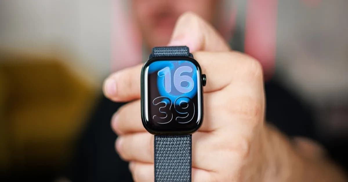 Seorang pria memegang Apple Watch Series 11 di tangannya, menampilkan tampilan jam.