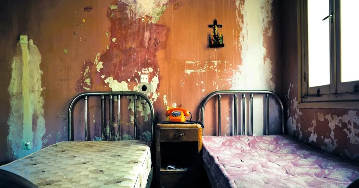 Ilustrasi kamar hotel kumuh dengan tempat tidur tanpa seprai dan telepon di antaranya