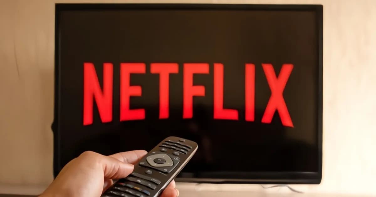 Netflix logo on a TV screen with a hand holding a remote control