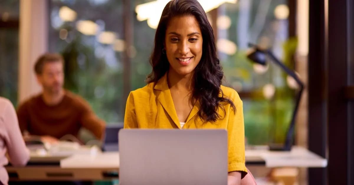 Wanita muda bekerja menggunakan laptop di ruang kantor yang santai