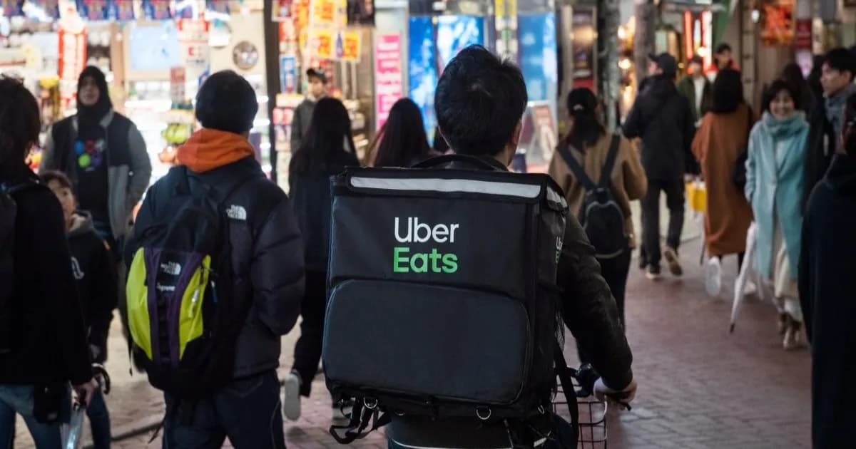 Logo Uber dan Delivery Hero dengan latar belakang peta global