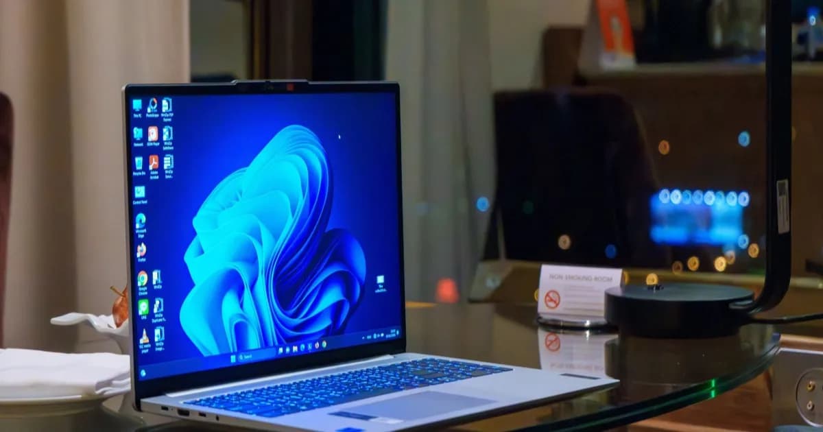 Ilustrasi laptop dengan tampilan desktop Windows 11 bercahaya di atas meja kerja