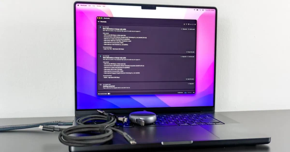 A MacBook Pro running the WhatCable app with several cables on top of its keyboard
