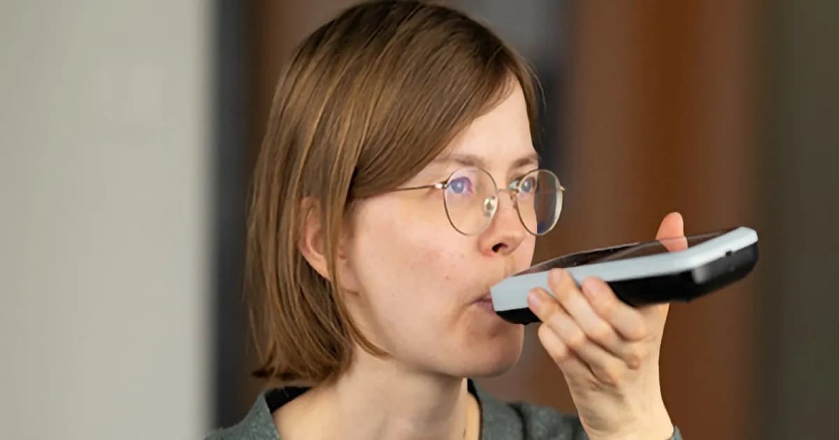 Seorang wanita sedang meniup alat breathalyzer Nutrion untuk mengukur pembakaran lemak tubuh