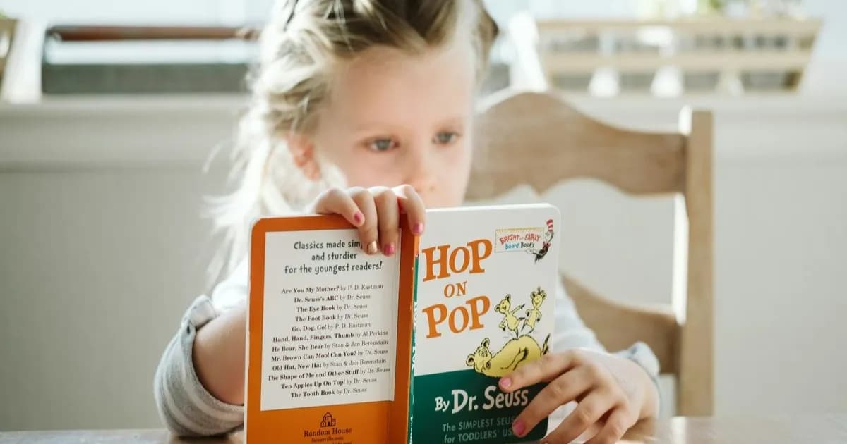 Seorang anak sedang membaca buku di rumah