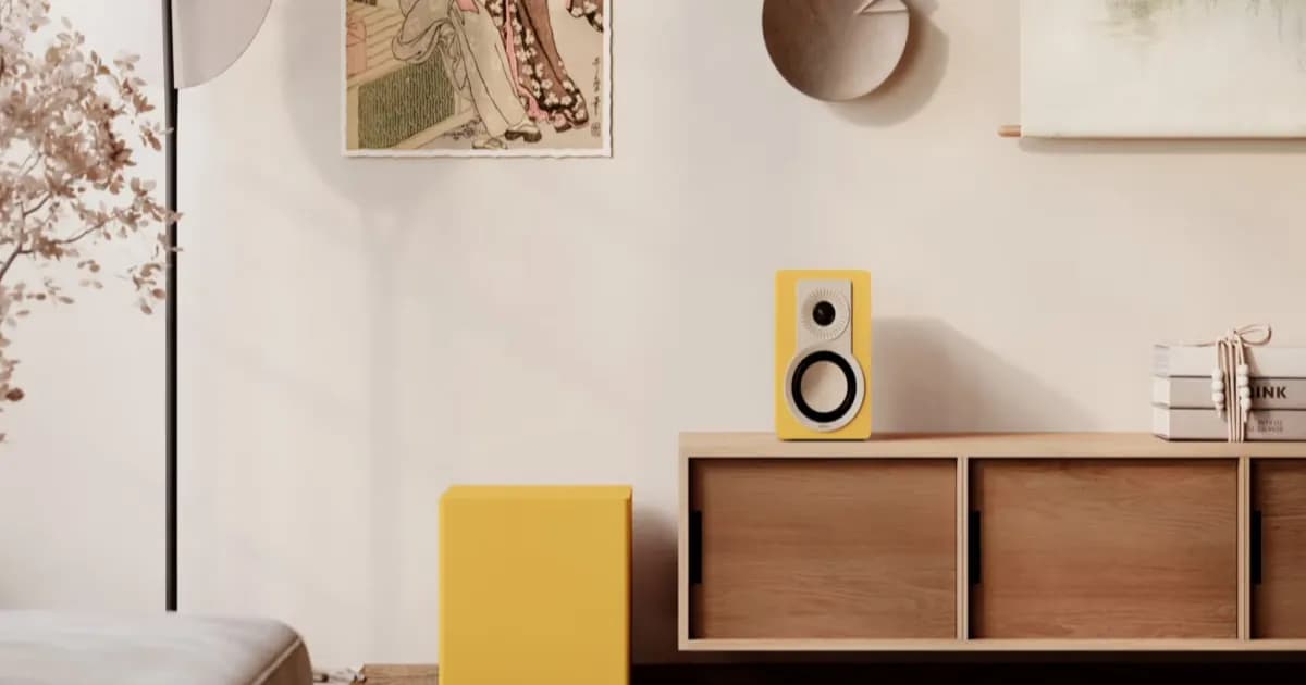 Dali Basik Sub subwoofer kuning di samping sideboard dengan speaker Dali kuning di atasnya