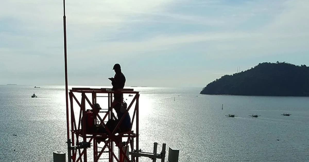Ilustrasi kapal di tengah laut dengan sinyal komunikasi yang dipengaruhi jarak, antena, dan cuaca