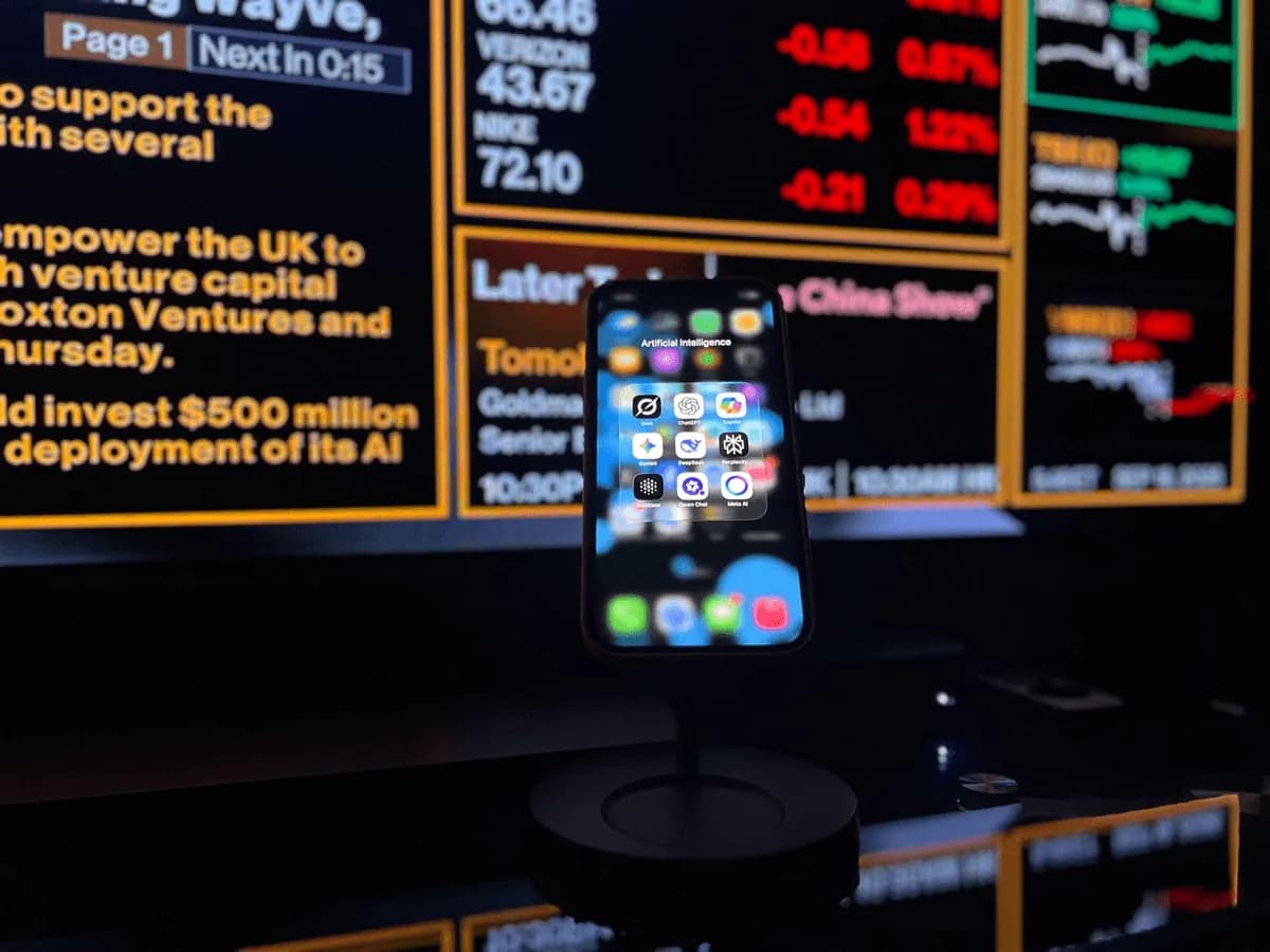 Smartphone di depan layar informasi pasar keuangan untuk ilustrasi AI agent dalam trading kripto.
