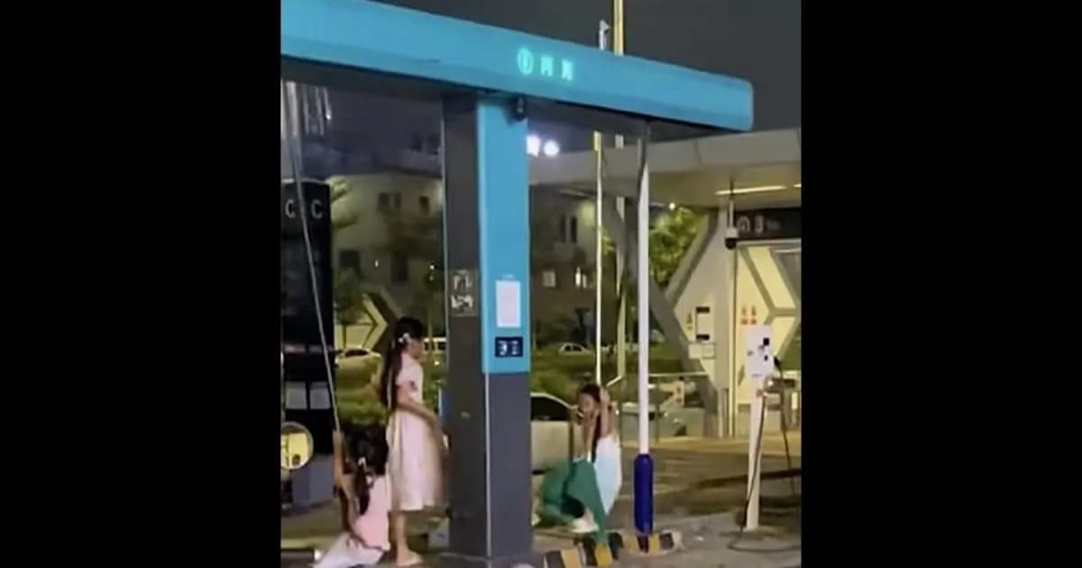 Dua anak berayun pada kabel liquid-cooled charger BYD Megawatt Flash Charging di stasiun pengisian daya publik Nanning, China