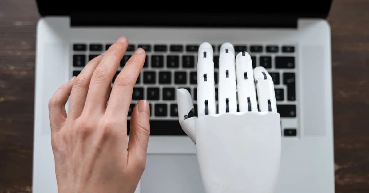 Ilustrasi tangan manusia dan robot di atas keyboard laptop, menggambarkan kolaborasi AI dan manusia dalam coding dan tugas digital