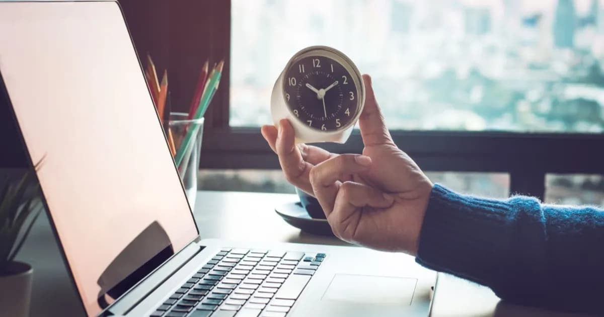 Pekerja mengetik di laptop sambil memeriksa hasil kerja AI di meja kantor
