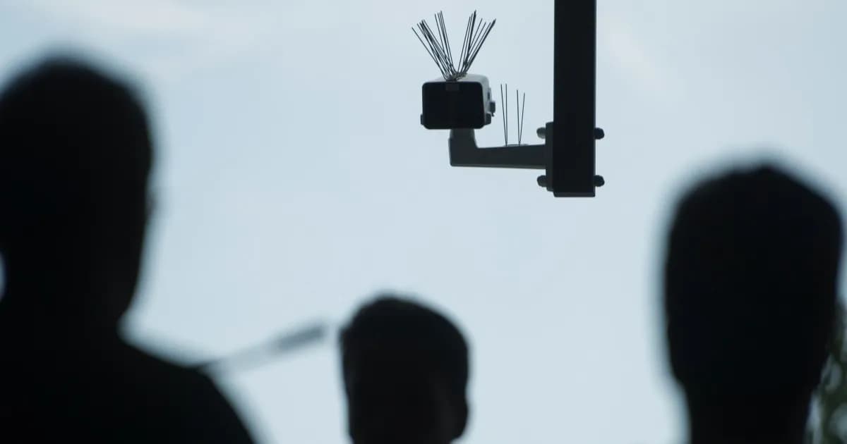 Siluet orang berjalan di bawah kamera pengawasan facial recognition