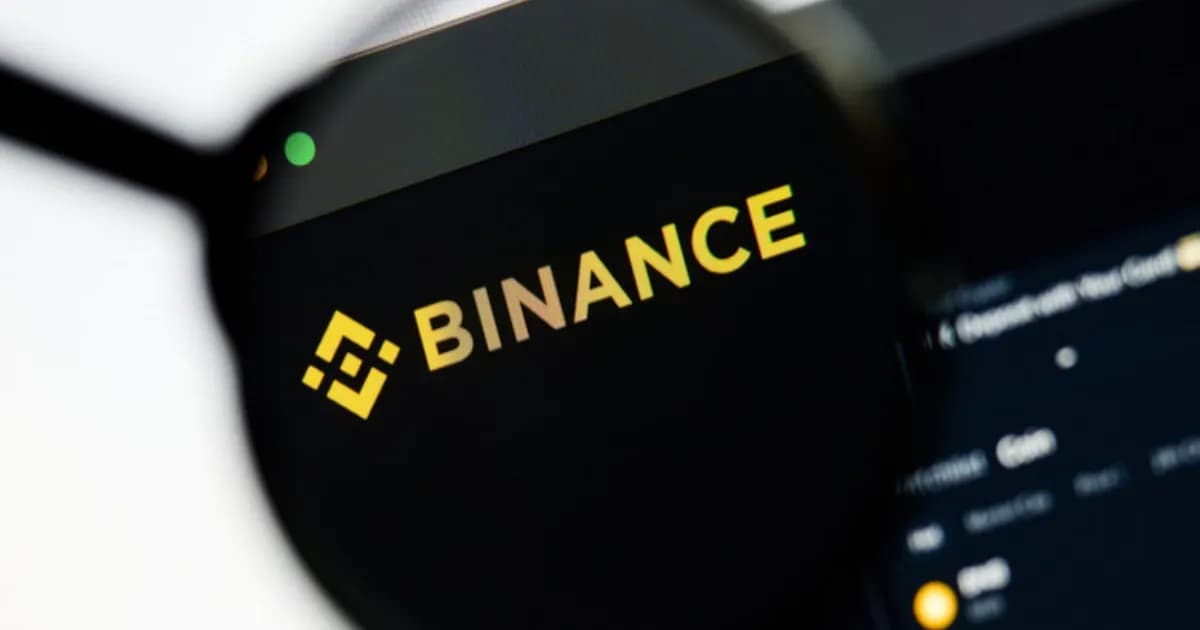 Logo Binance di bawah kaca pembesar dari layar komputer