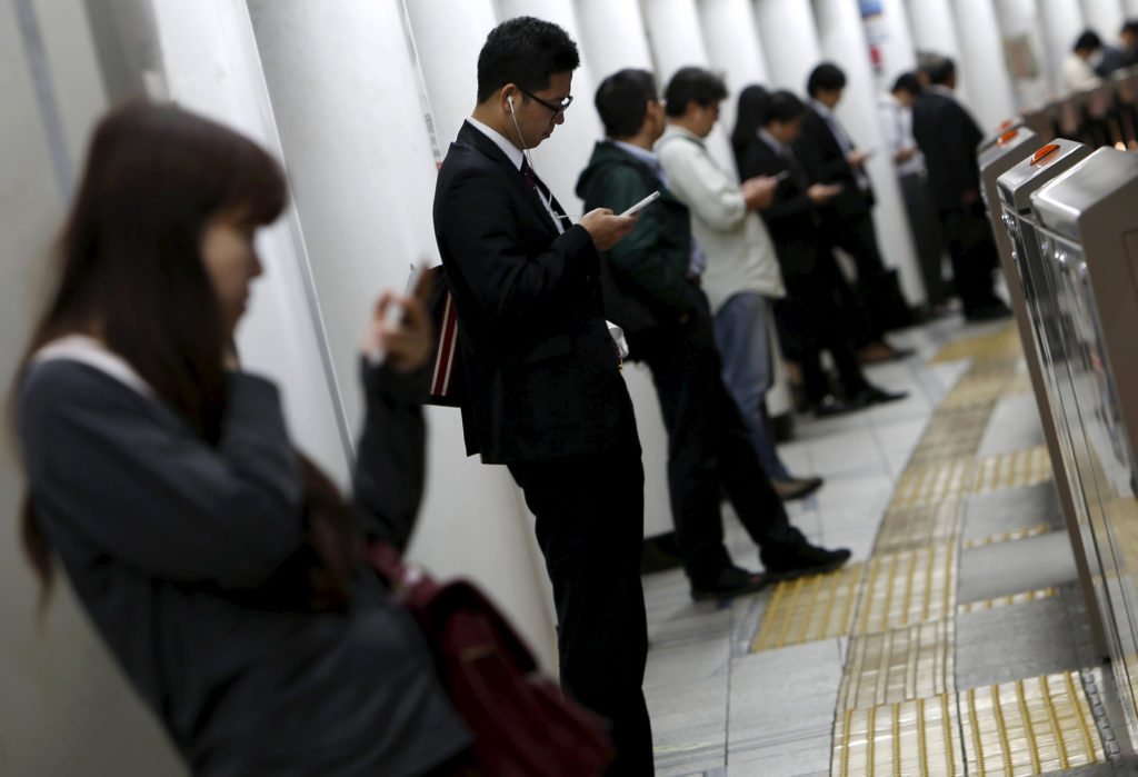 People look at their mobile phones while waiting for a train at a subway station in Tokyo, Japan, October 14, 2015. Japanese manufacturers' confidence worsened for the second straight month and is expected to fade going forward, a Reuters poll showed, adding to lingering fears of a recession and keeping policymakers under pressure to deploy fresh stimulus. Picture taken October 14, 2015. REUTERS/Yuya Shino