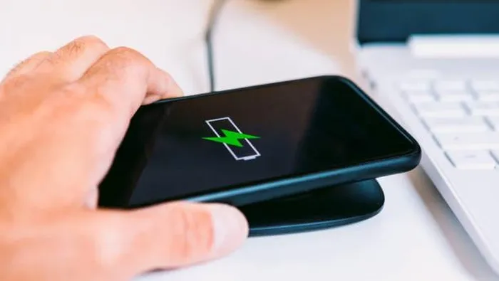 Ponsel Xiaomi sedang di-charge di wireless charger dengan indikator baterai di layar