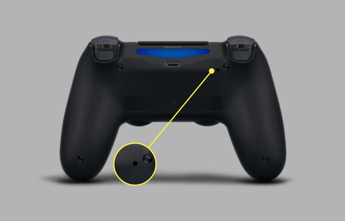 A DualShock 4 controller with the reset hole highlighted