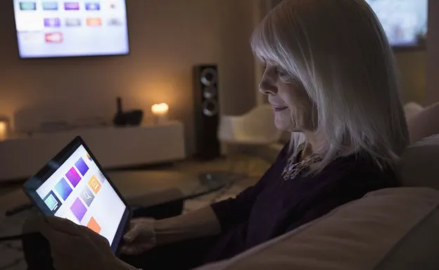 Person using smart TV apps on digital tablet on living room sofa