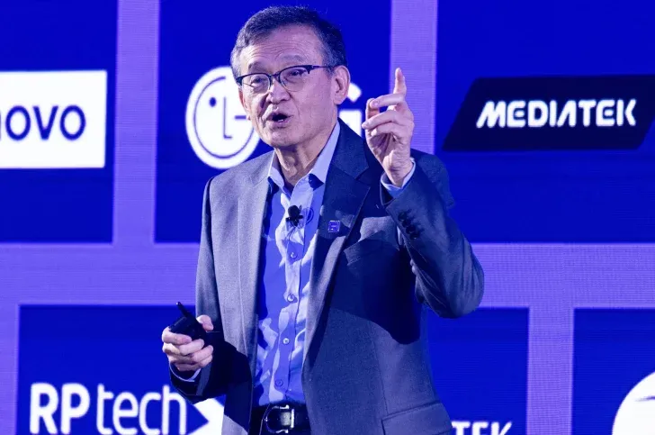 Intel CEO Lip-Bu Tan at a tech conference with logos in the background.